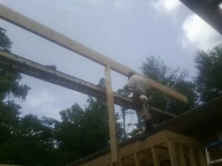 Carpenter setting a ridge beam over a new addition frame — Ice Dam Removal by Roofing Brothers in Fosters