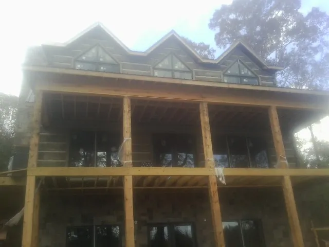 Dormers and porch framing on a large log home under construction — Roof Coating work by our crew in Fosters