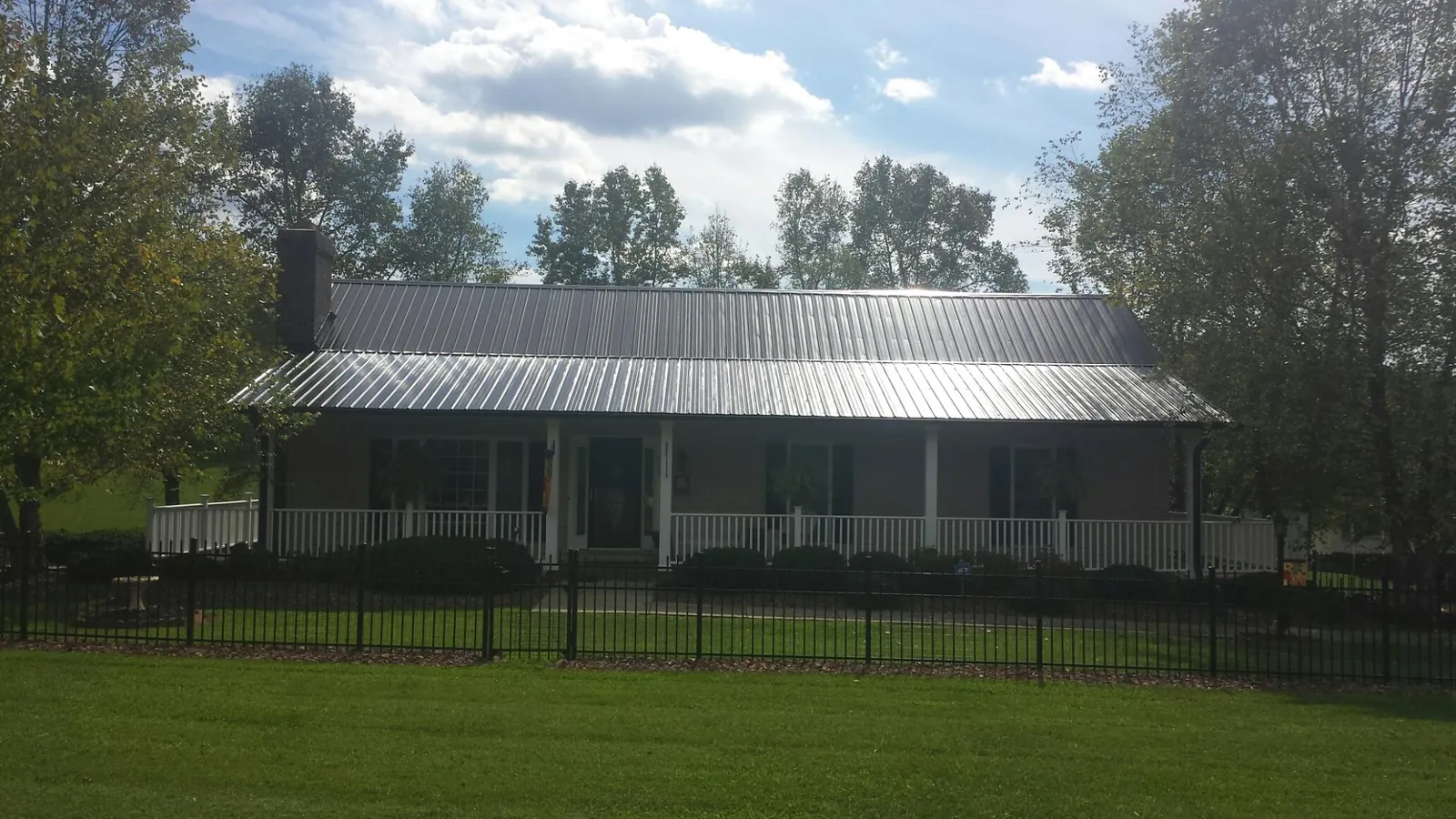 Gray metal roof on a brick ranch with a full width front porch — Gutter Guard Installation work by our crew in Fosters