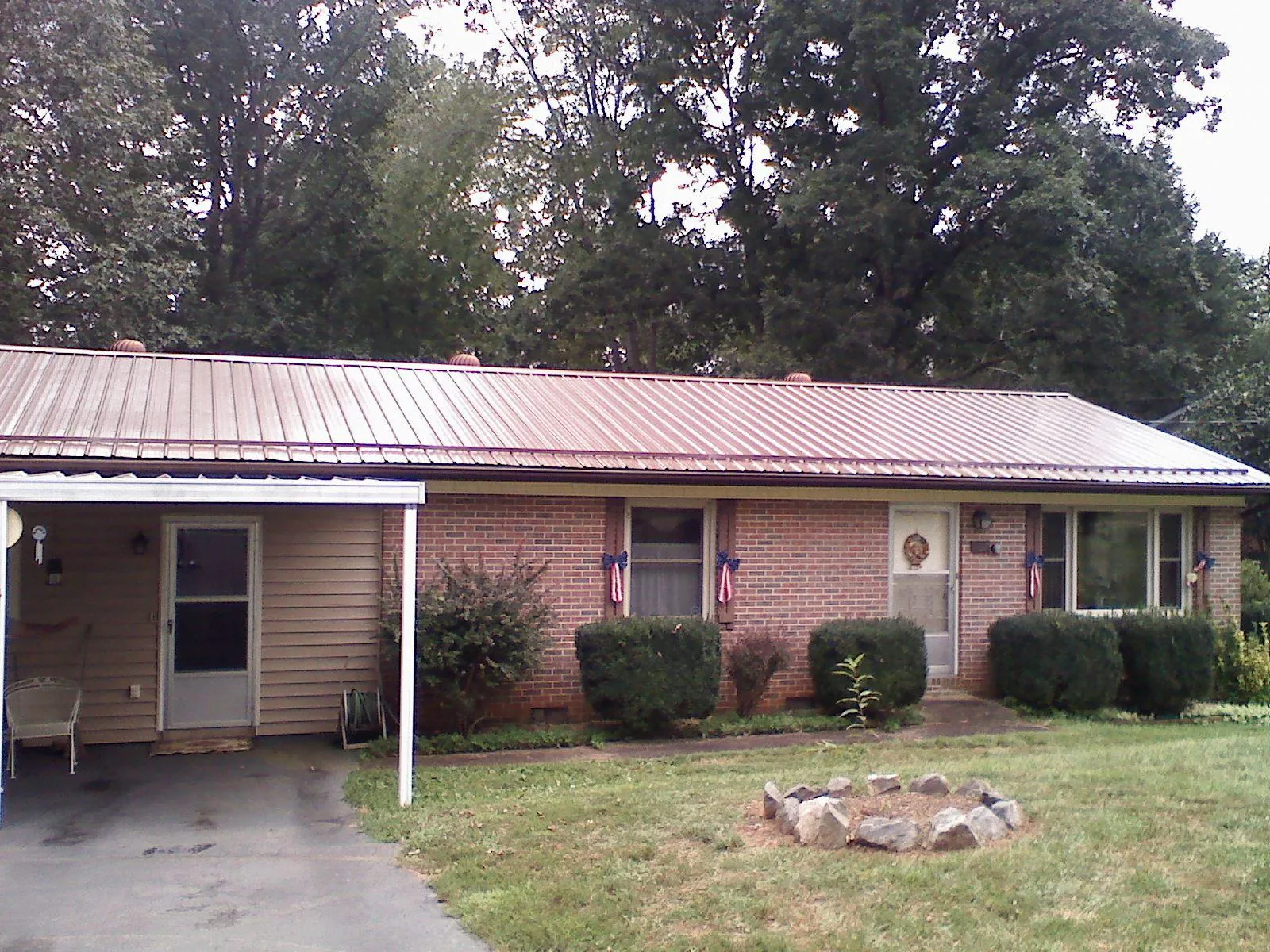 Bronze metal roof and carport on a brick ranch home — Roof Repair work by our crew in Fosters